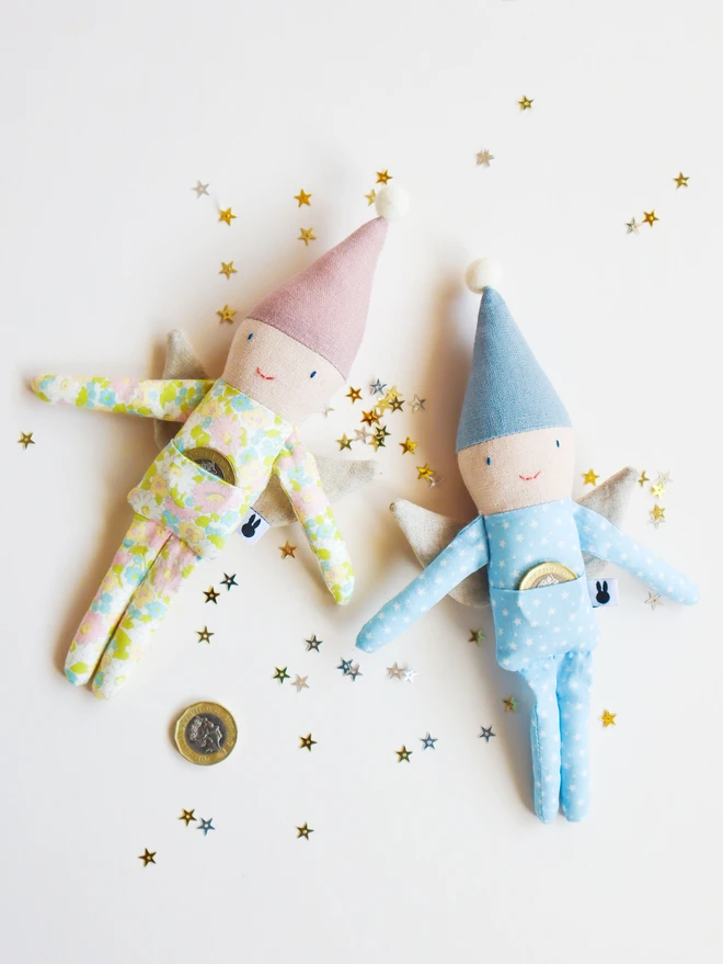 Small fairy dolls in blue and pink linen pointy hat, blue star and pink floral printed outfit and natural linen wings.