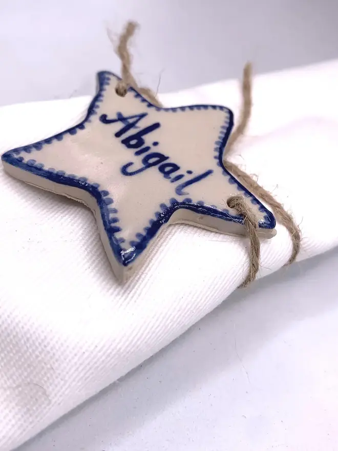 Personalised Ceramic Christmas Star Name Place Markers, a colourful star place marker sitting on a plain white surface. 