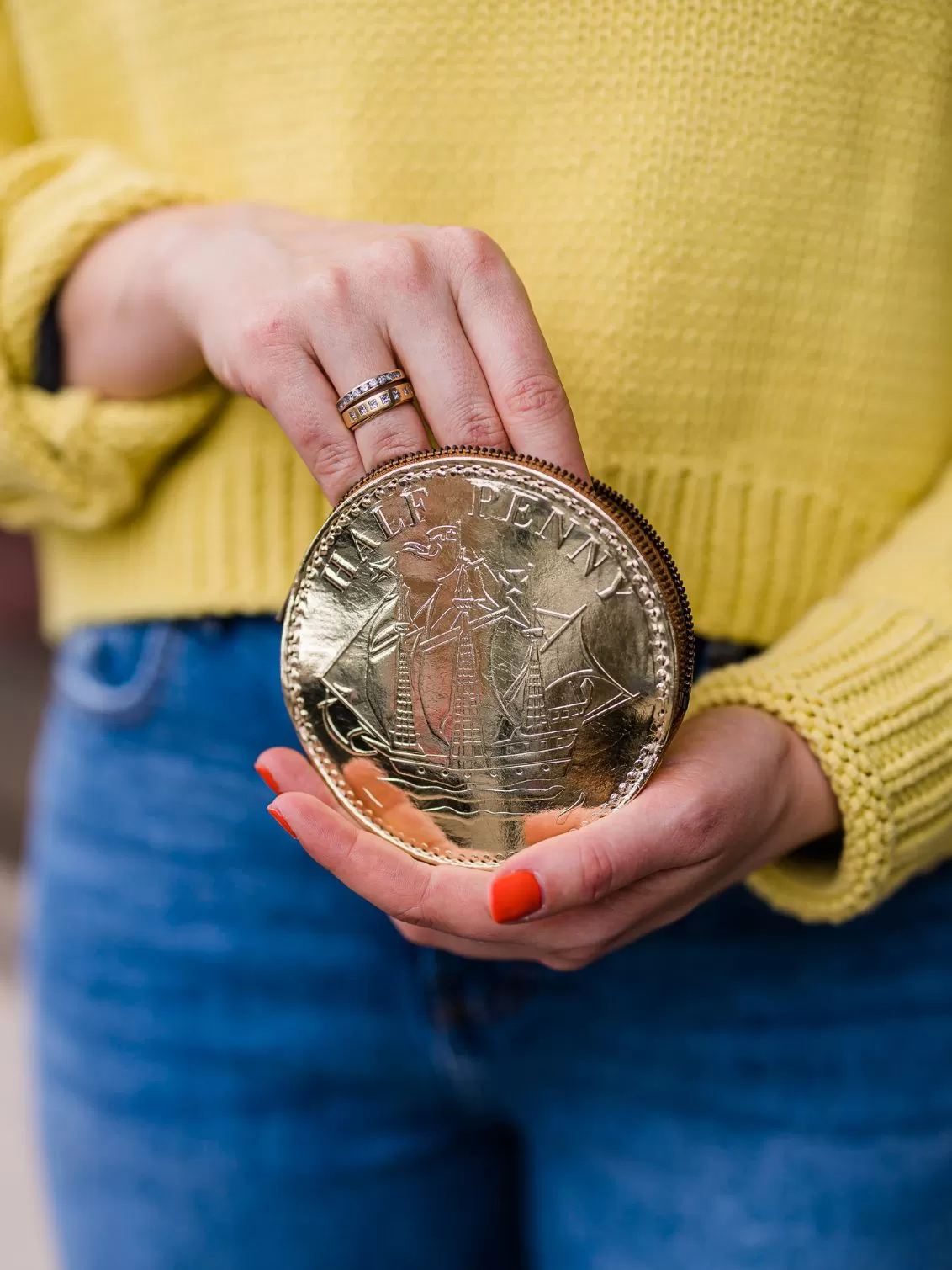Fun Sized Gold Leather Half Penny Purse seen held by someone wearing a yellow jumper.