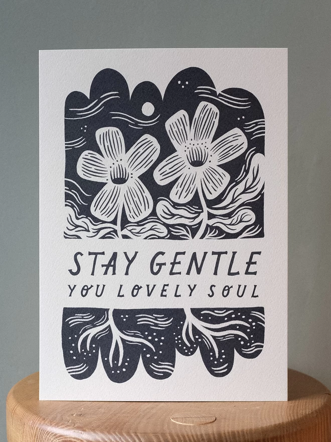 An art print containing the phrase 'Stay Gentle' with black and white flowers and lino cut style botanicals