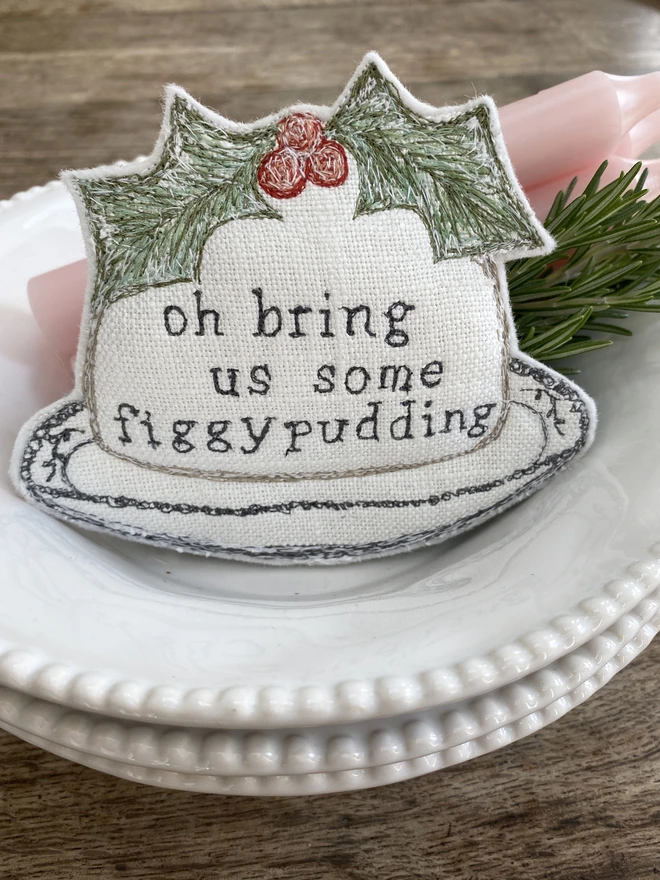 Figgy Pudding Embroidered Fabric Decoration on a plate with candles