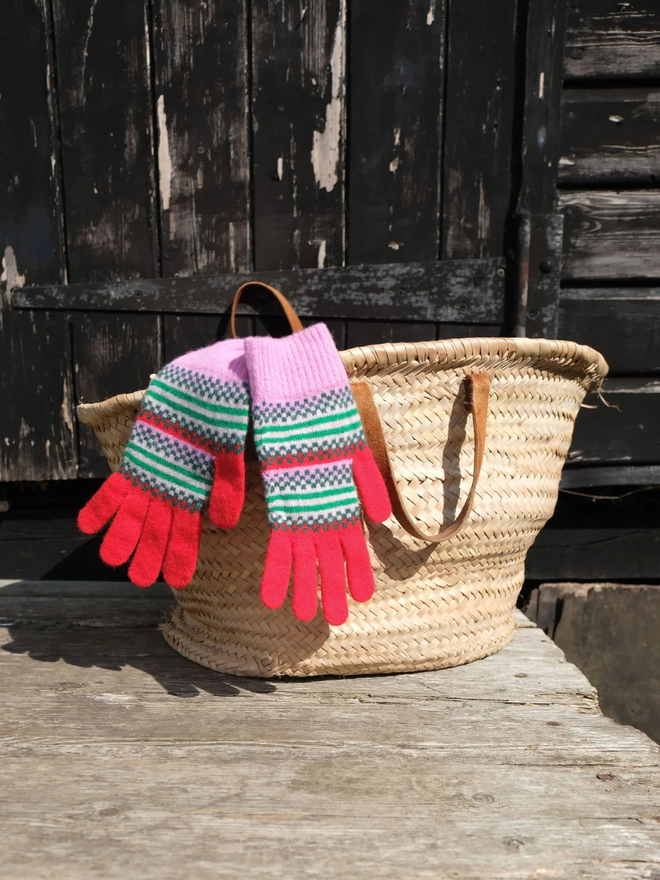 Red fairisle gloves. Red fairisle with a pink trim on top of a wicker basket