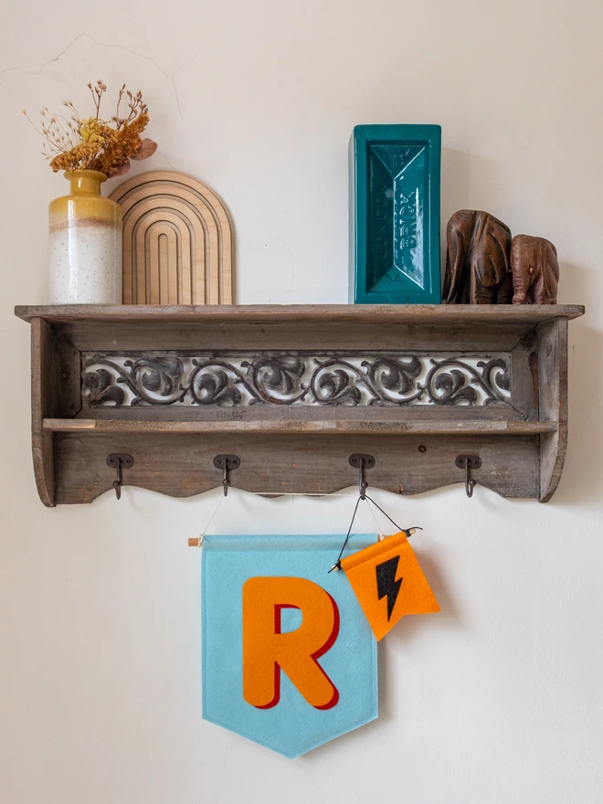 A bright blue banner with the initial "R" on the front. The initial is in orange and has a red drop shadow effect.