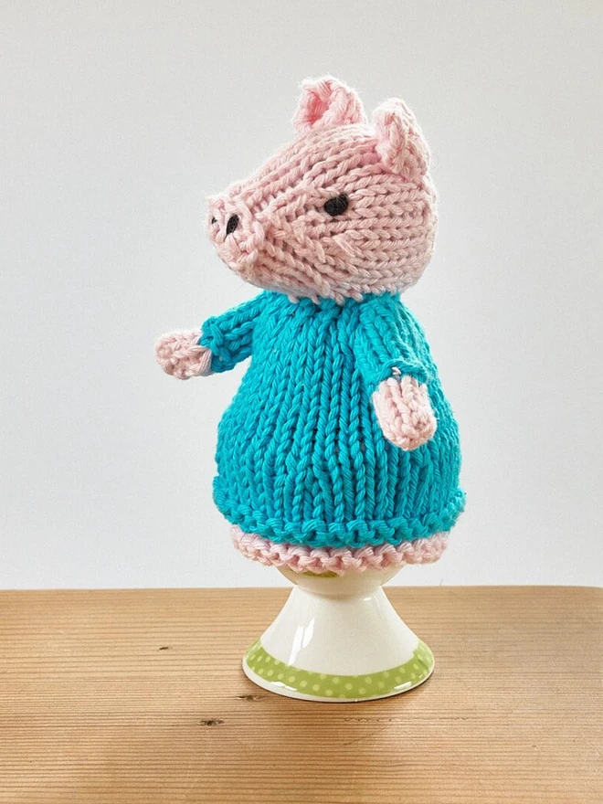 Egg Cosy Pigs Table Decoration (Set Of 2), a colourful pig cosy sitting on a wooden surface. 