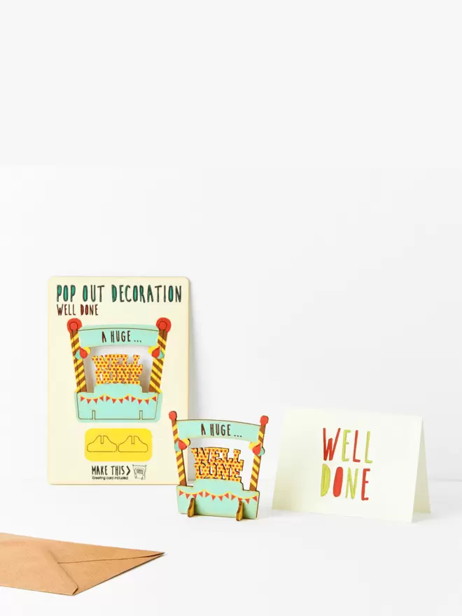 Well done pop out decoration and well done card and brown kraft envelope on a white background