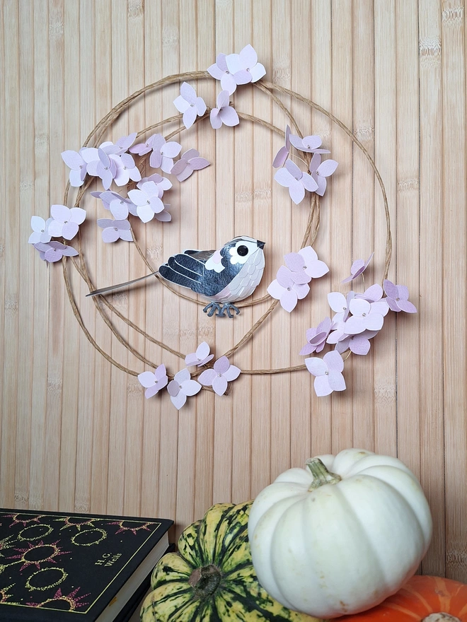 pink floral wreath depicting a long tailed tit bird