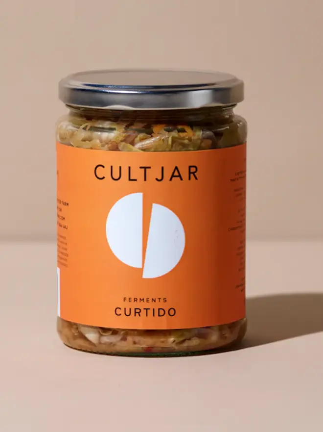 jar of curtido ferment with orange label