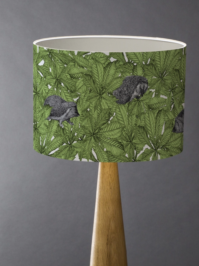 Drum Lampshade featuring hedgehogs in green leaves with a white inner on a wooden base 