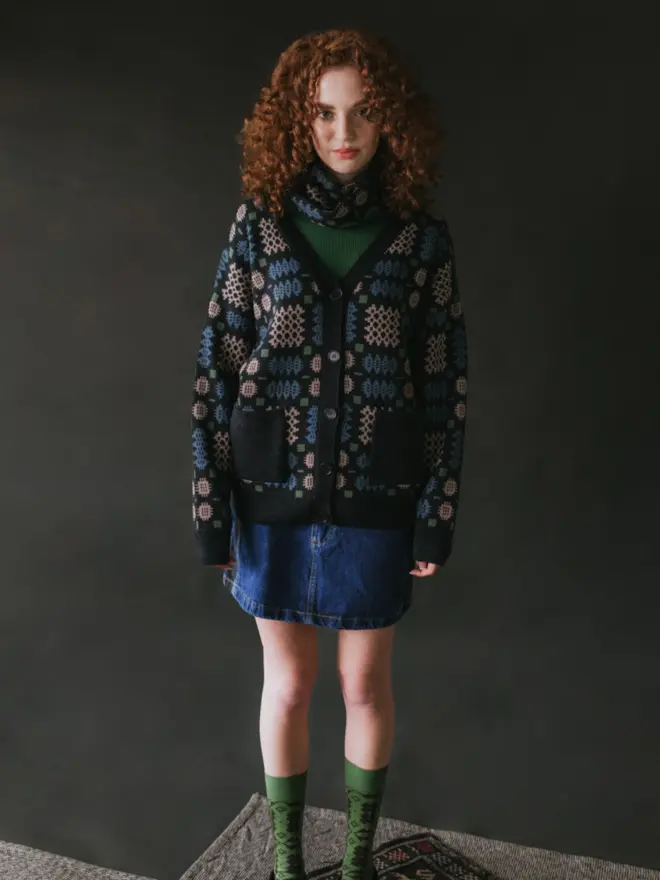 Model wearing pieces from MABLI's 'Carthen' collection, featuring the Carthen Cardigan in the vibrant 'Emeralds' colour-way. The design showcases bold, colourful patterns inspired by traditional Welsh blanket tapestry.