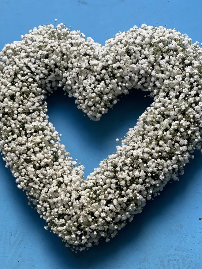 White Gypsophilia Heart Wreath against a blue background