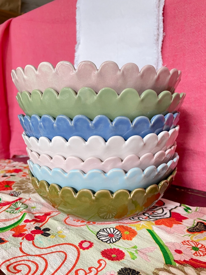 stack of small serving bowl with daisy scallop edge. Olive green, heaven blue, blossom pink, white, periwinkle blue. sage green, blush pink