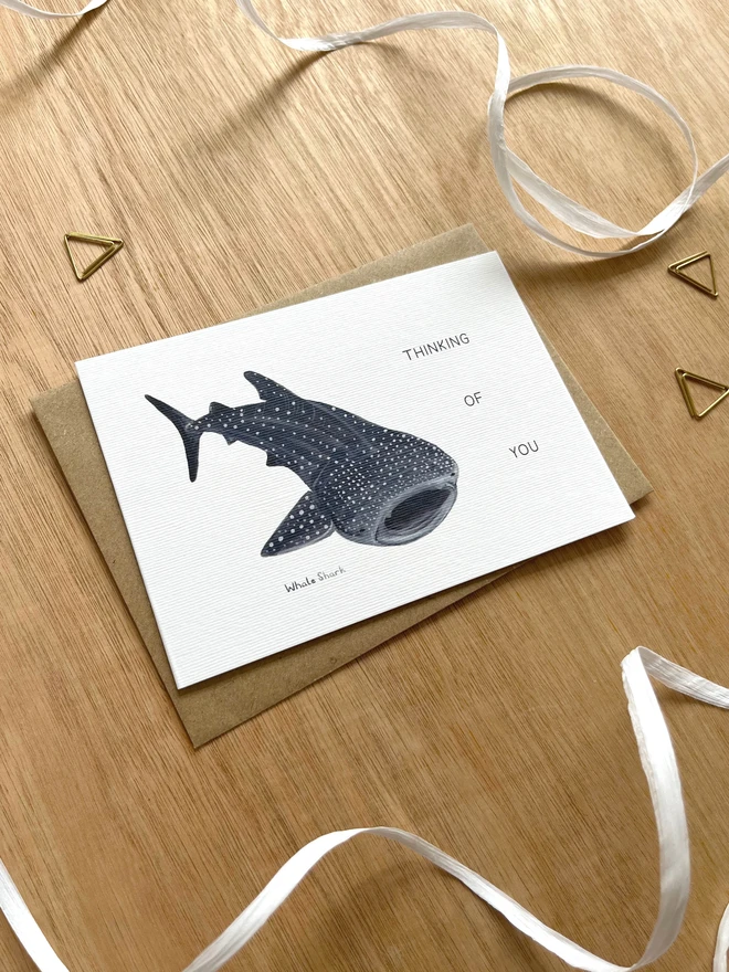 a greetings card featuring an illustration of a whale shark with the text “Thinking of you”
