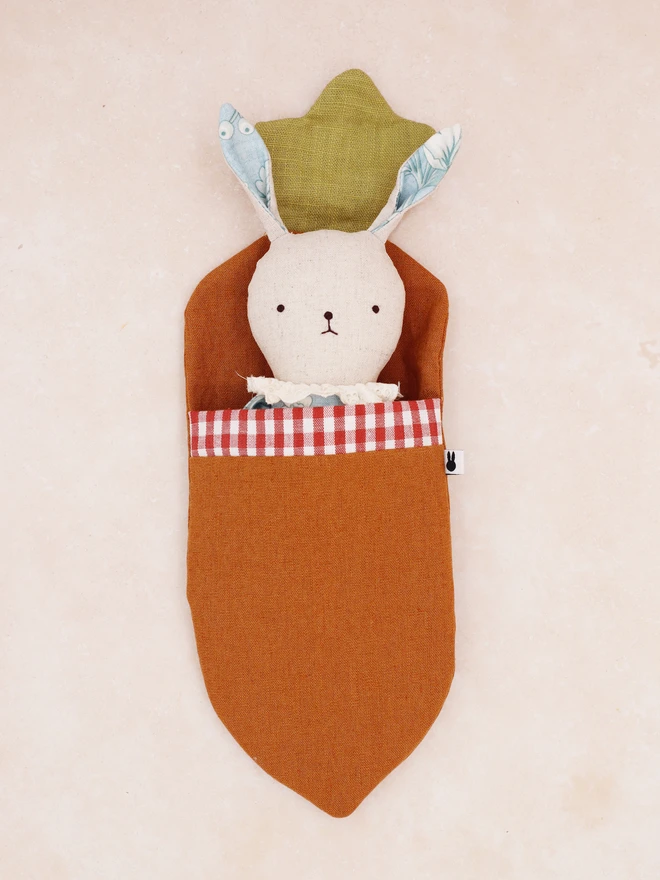 Handmade easter bunny doll with natural linen, floral blue cotton outfit and broderie anglaide lace frill collar, snuggled in a carrot shaped sleeping bag made with linen brown and green linen and brown gingham cotton.