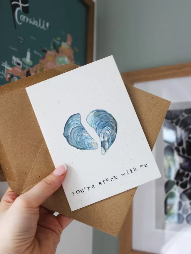 'You're Stuck With Me' Card being held up against coastal artwork