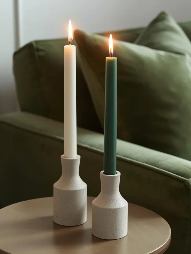 evergreen dinner candle in a candle holder on a side table next to a sofa
