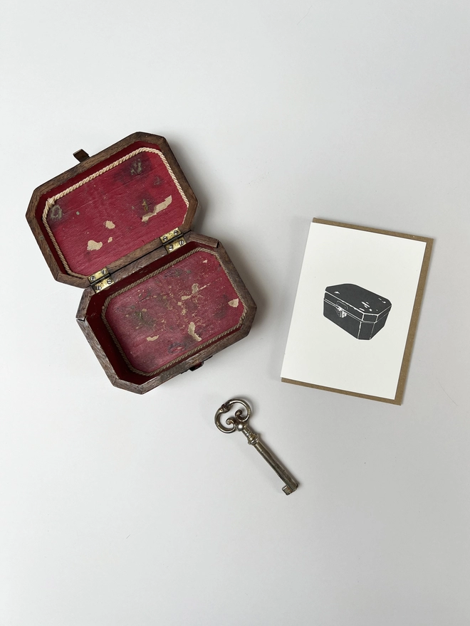 The small card with a letterpress printed chest on it with a vintage box and key next to it