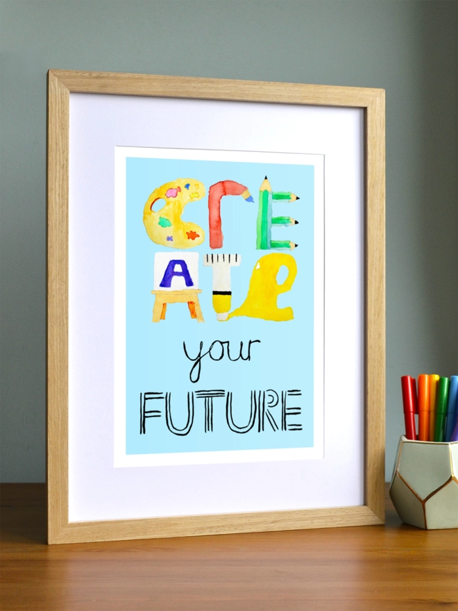 Art print saying 'Create your future' in a brown frame in a child's room