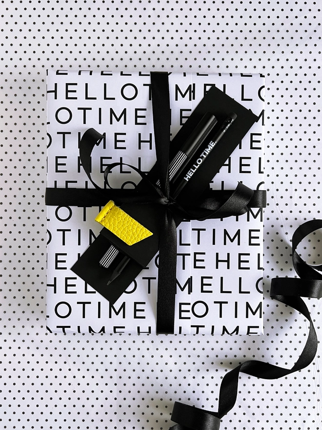 HELLO TIME Life Planning Kit wrapped in monochrome paper with black ribbon, pencil, fineliner and yellow leather page marker attached