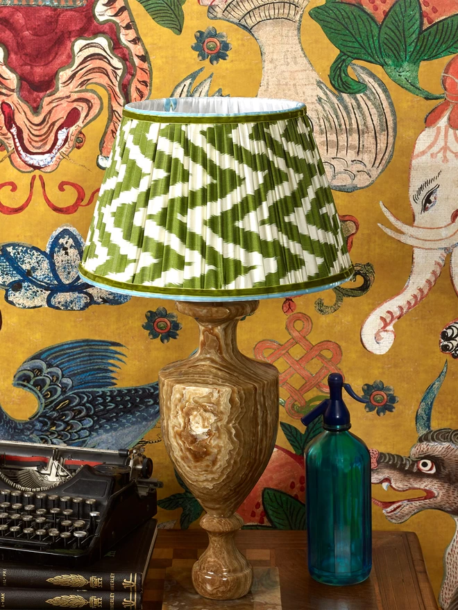 Maximalist Interior Design: Classic Green Silk Ikat Lampshade on Table in Patterned Wallpapered Room