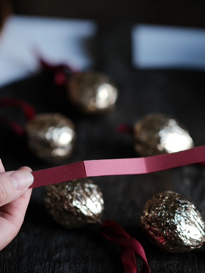 Handmade walnut Christmas ornament with delicate gold gilding, showing the natural shape and grain of the wood. A traditional, nostalgic Christmas tree decoration with timeless old-fashioned charm.