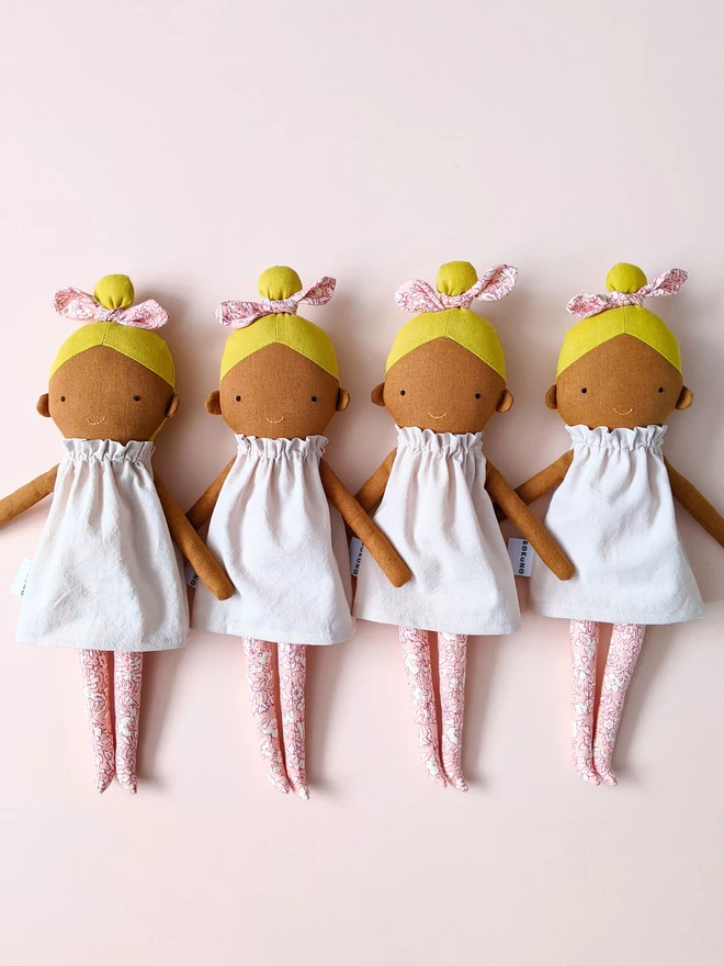 four dolls with blond hair and dark skin