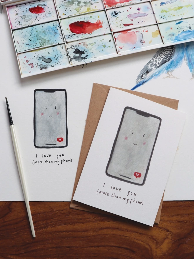 I Love You More Than My Phone Valentines Day Card.  The Card design has an illustrated I Phone with a smiley face 