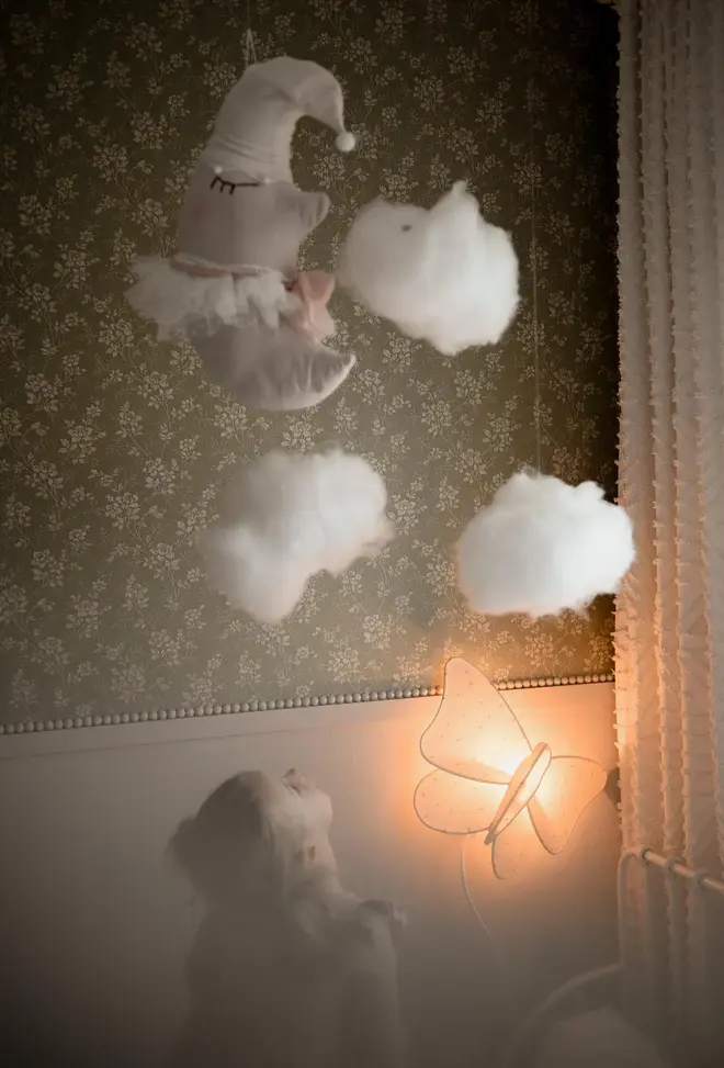 Sleepy Moon Nursery Pillow Hanging Decoration, a hanging pillow decoration suspended in a bedroom. It is joined by other decorations. 