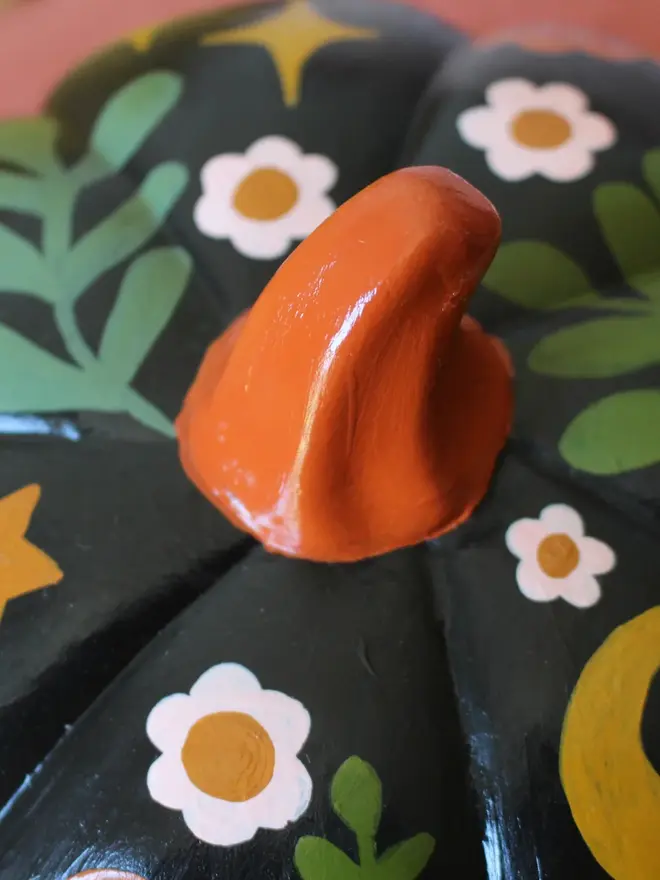 hand-painted folk art ceramic pumpkin. a black ceramic pumpkin painted with mushrooms and flowers.