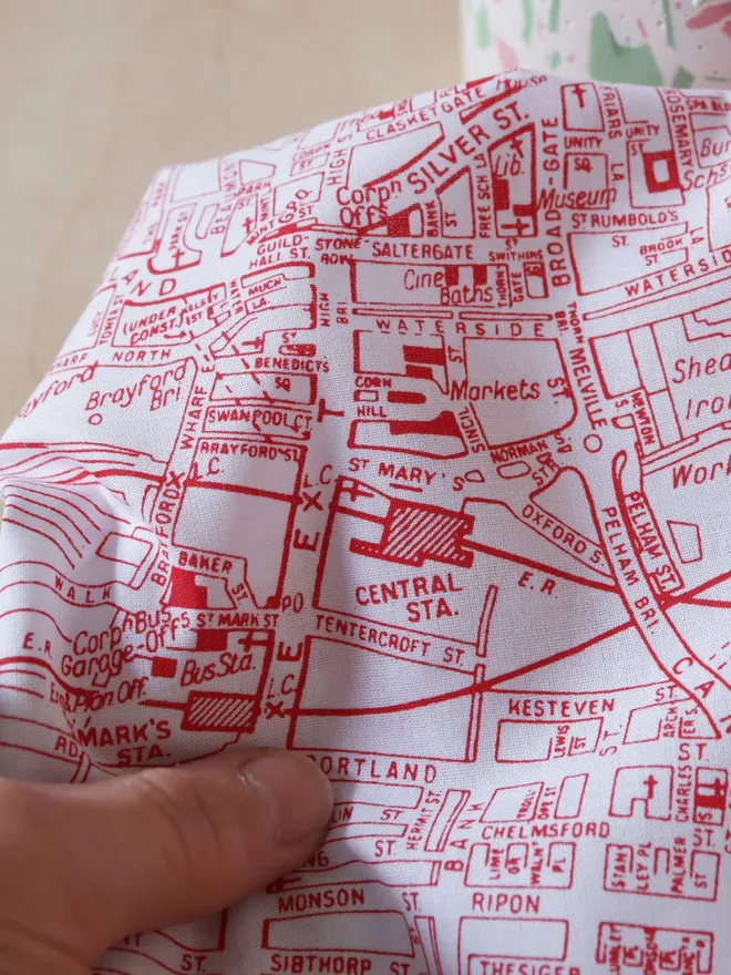 Mr.PS Lincoln Map Handkerchief screenprinted in red shown in detail held by a white hand