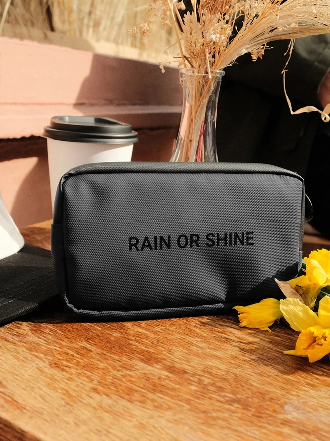 grey case with 'rain or shine' text on wooden table
