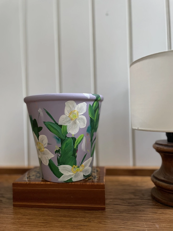 Unique hand-painted terracotta pot featuring white anemone flowers on a lilic background