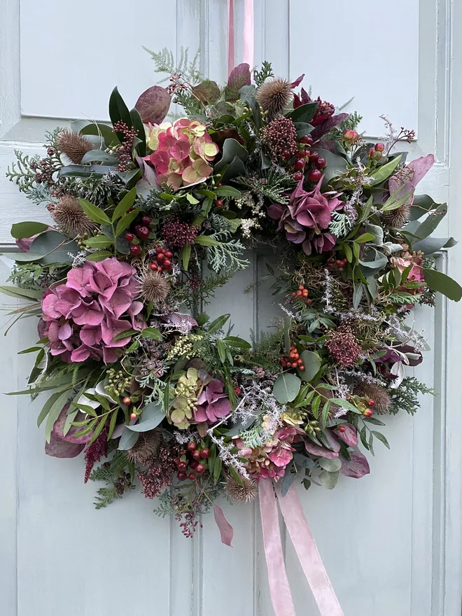 Floral wild hydrangea door wreath. a wreath hung on a white door made up of foliage and wild hydrangea flowers.