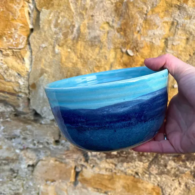 Landscape Ramen Bowl, a colourful ramen bowl held in front of a brick backdrop. 
