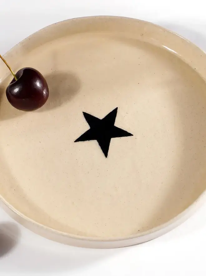 Handmade Ceramic Side Plate With A Black Star Design, a ceramic side plate with a black star design sitting on a white table. 