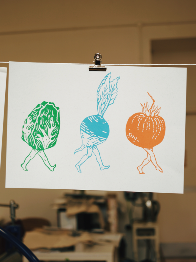 A print showing 3 vegetables with legs walking across the page