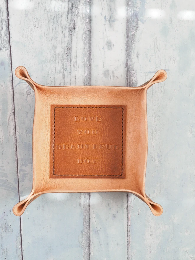 Personalised message leather coin tray. Hand dyed tan brown leather tray with a square stitched to the base which is personalised with a short but sweet message.