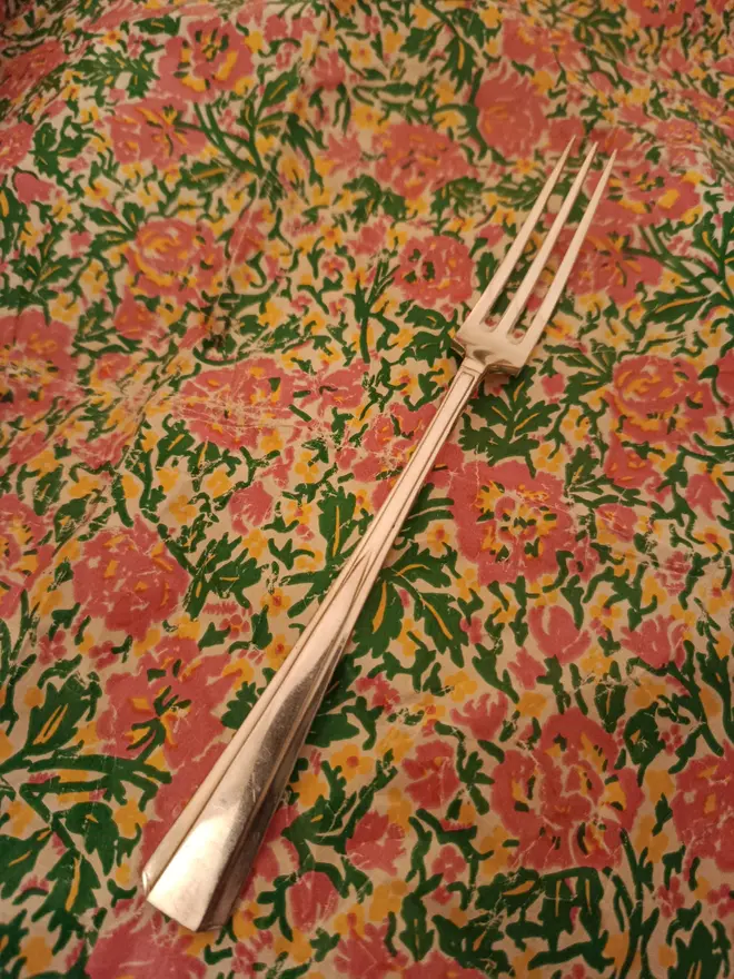 Three pronged pickle fork on a floral background 