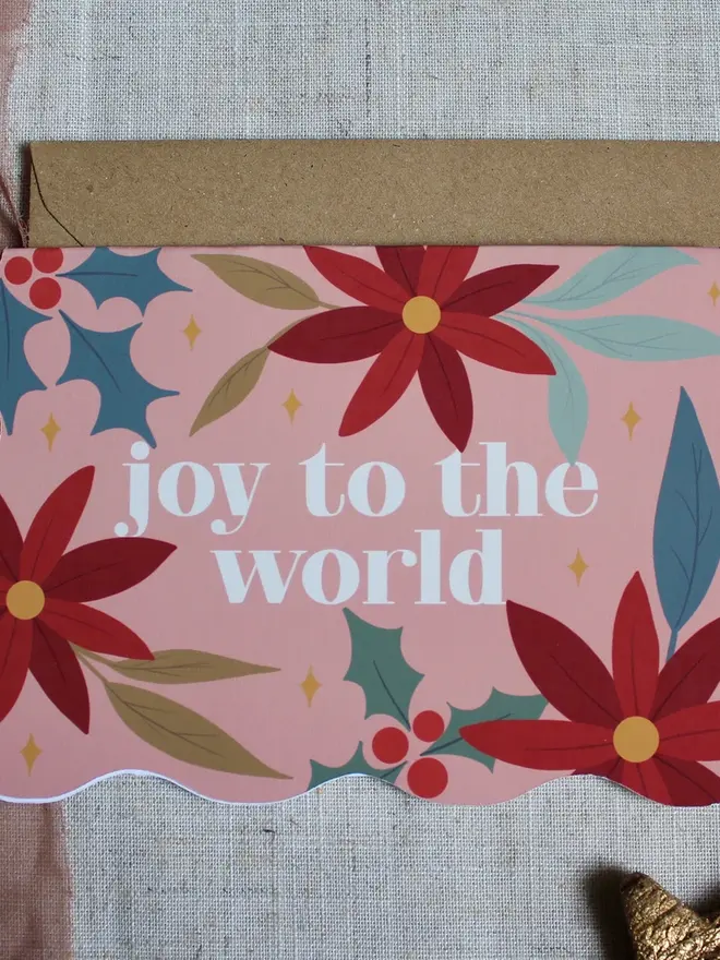 joy to the world floral christmas card. wavy edged pink floral card emblazoned with joy to the world.