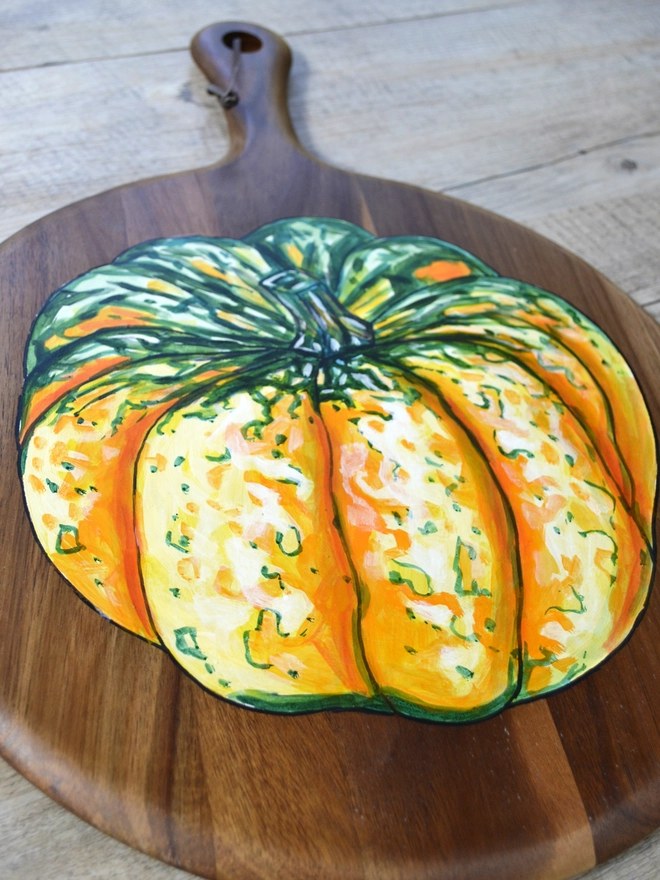 Wooden serving board with a handpainted design of a carnival squash