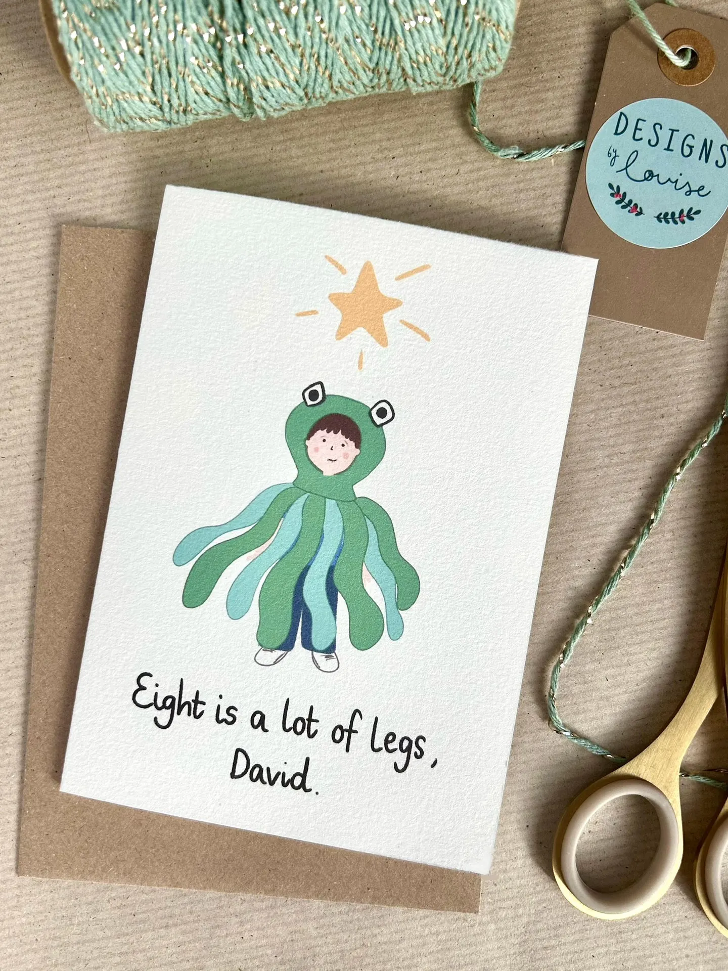 Cute illustration of a boy in an octopus costume from the nativity scene standing beneath a Christmas star. Below reads the quote "Eight is a lot of legs, David" from the film Love Actually.