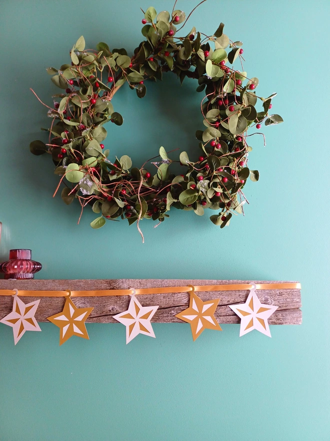 Gold and White 5 Pointed Star Garland Displayed on Mantelpiece With Wreath Above