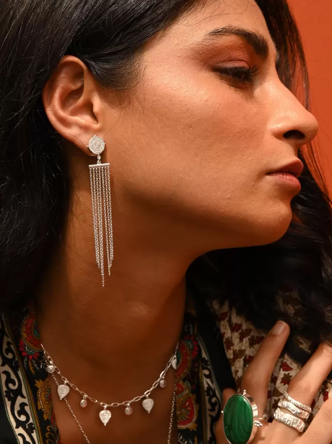 Model wearing long fringe compass earrings