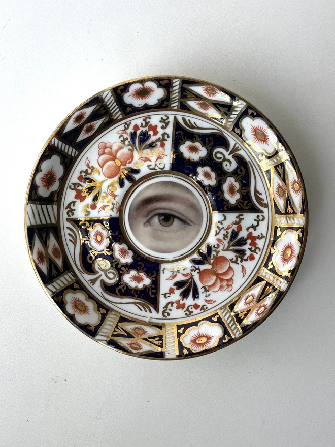 vintage plate with an ornate border, with a printed vintage illustration of an eye in the middle