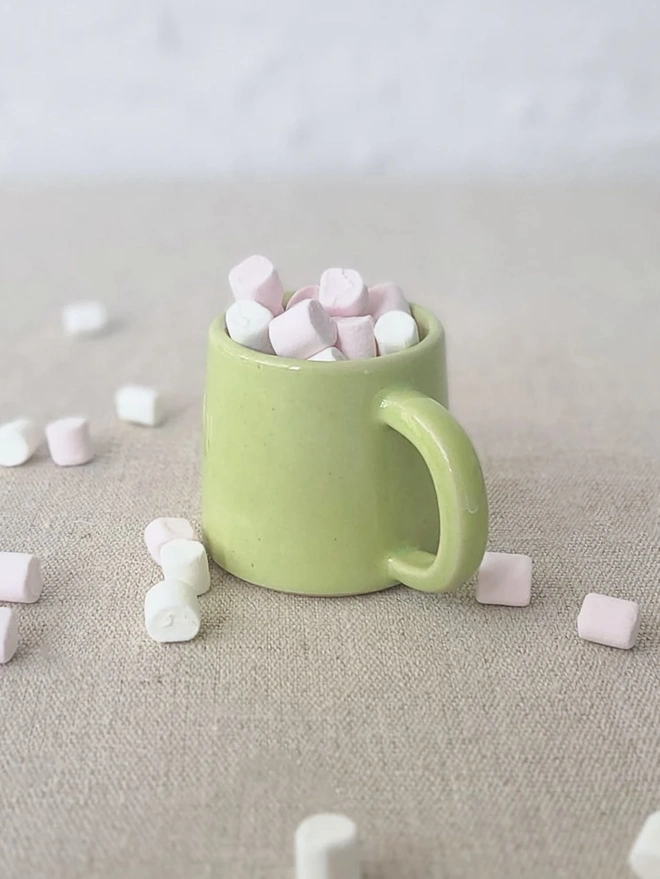 Classic Ceramic Espresso Mug, a colourful ceramic espresso mug sitting on a plain surface against a white backdrop. It is accompanied by a group of marshmallows. 