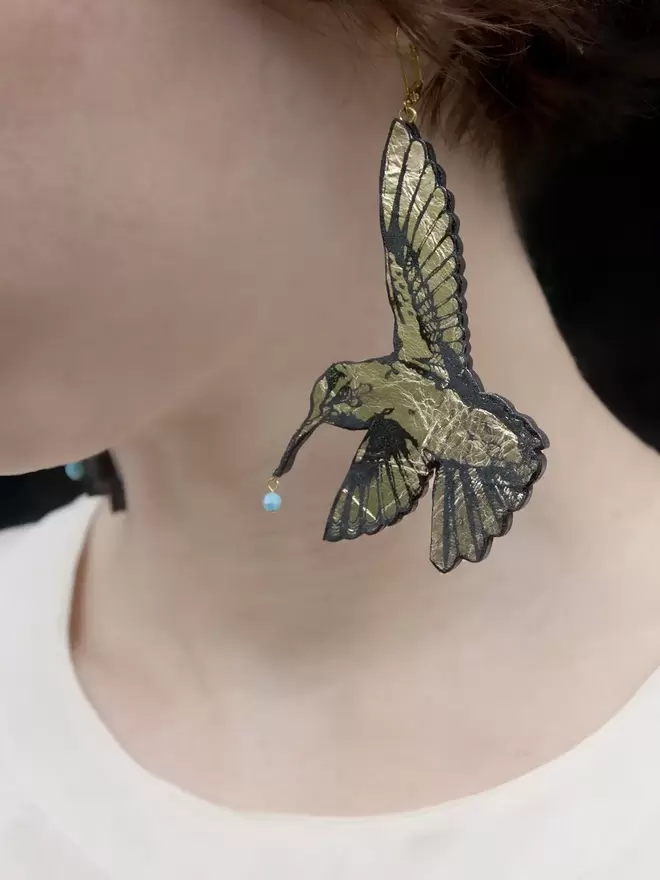 leather hummingbird earrings in gold on model