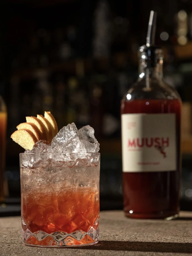 Rhubarb & Apple Elixir, a drink sitting on a stone surface in a bar accompanied by other bar equipment. 