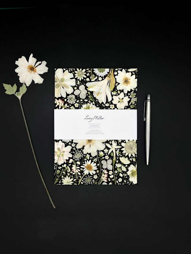 Lined Notebook with cover design created from pressed white flowers on a black background.