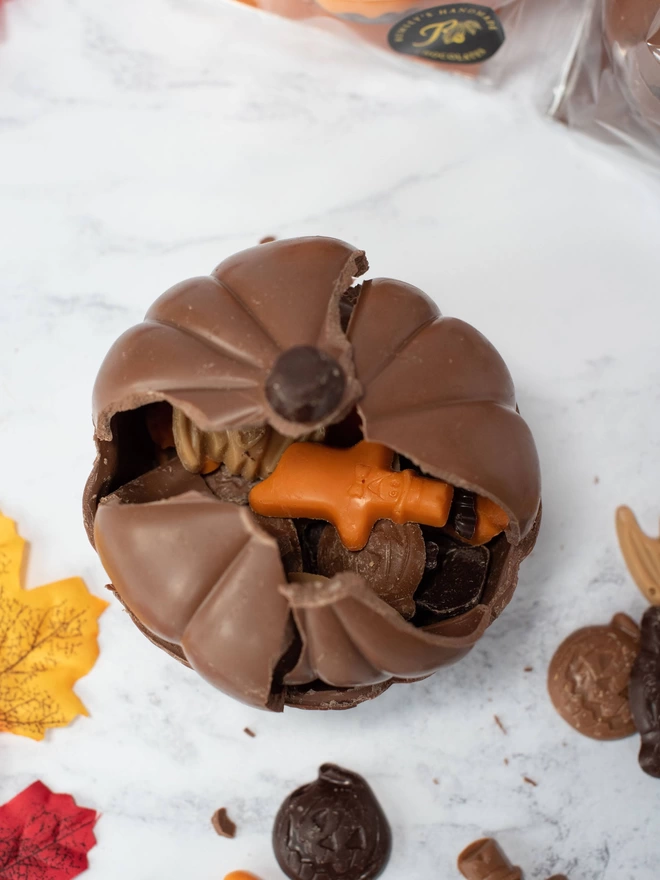 Smashed open chocolate pumpkin with assorted halloween chocolate shapes