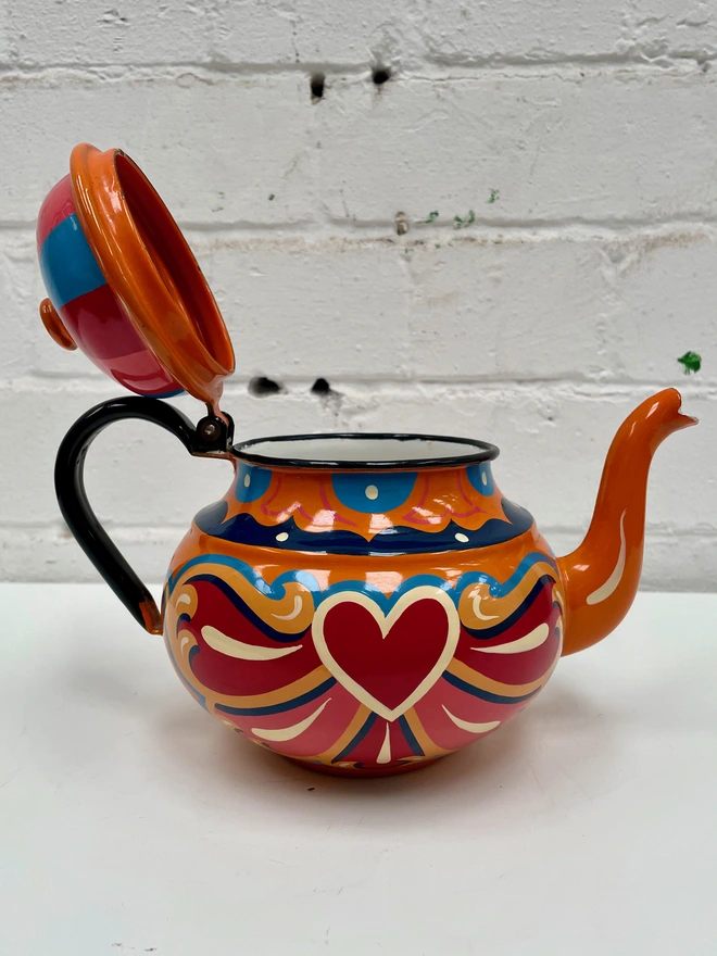 Orange vintage teapot with hinged lid, hand painted with a traditional fairground inspired design in pink, red, yellow and blue.