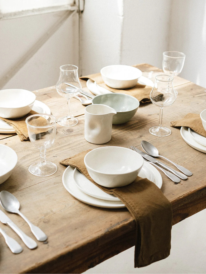 stoneware place setting dining set. a white plate setting set on a wooden table.